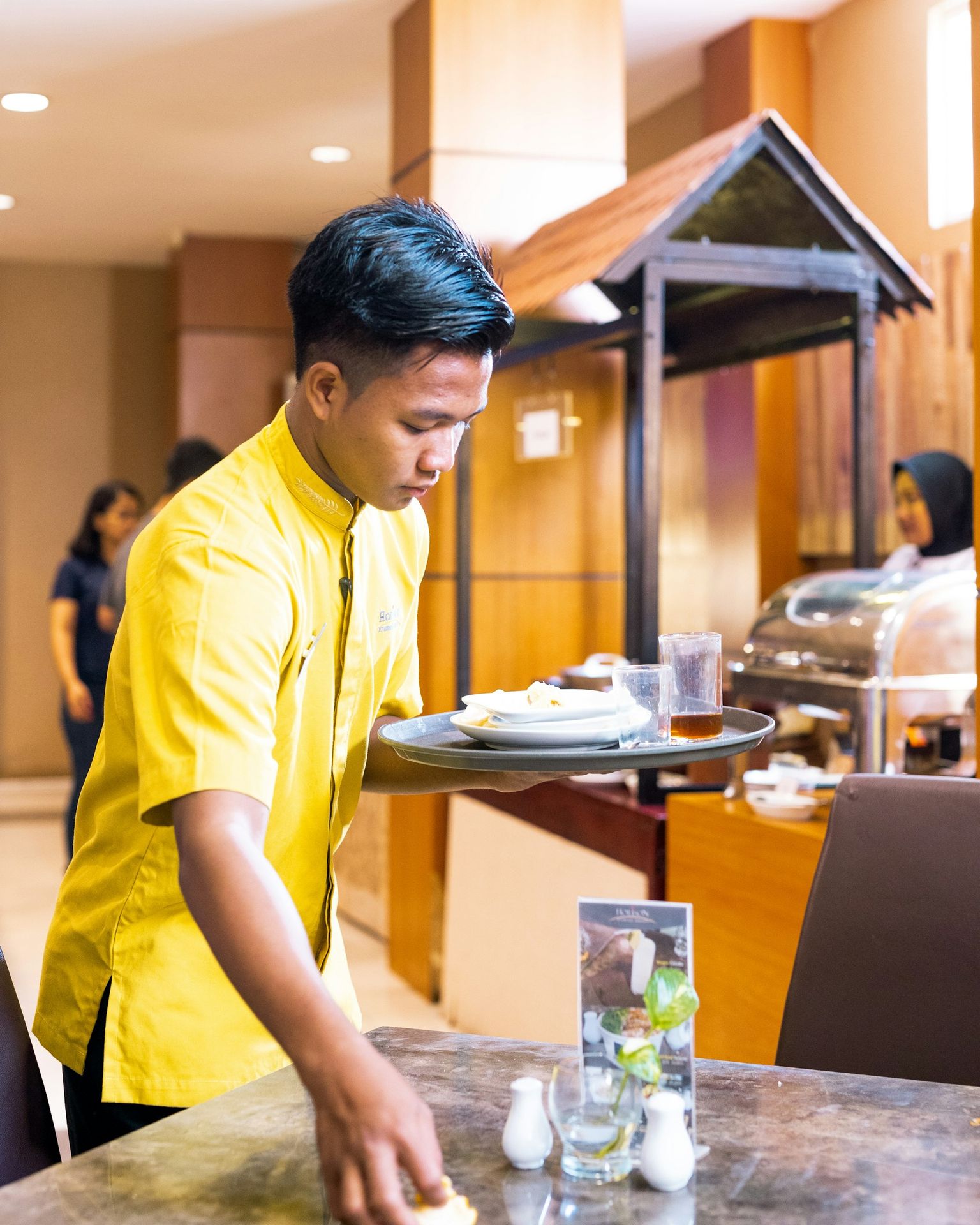 man in yellow polo shirt standing in front of table
